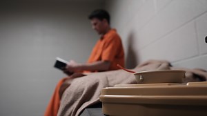 Christian Prisoner Inmate In Prison Cell Reading Bible
