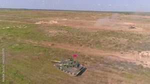 Cinematic slow-mo action footage of army tank shooting powerful canon in slow motion drone footage. Heavy armored military vehicle training to defend your way of life in dust and sand. Aerial view.