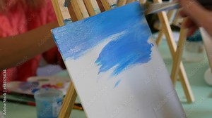 Drawing lessons. An artist's hand paints a picture on a canvas with a brush in the studio