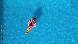 Relaxed girl on an inflatable mattress in the pool in the summer relaxes and swims, shot from above by a drone