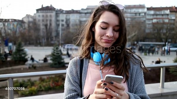 Girl texting on her mobile phone and looking at camera