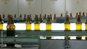 technological line for bottling of beer in brewery, bottles are moving against lights