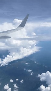 View from airplane window and wings next to the window. Airplane flying with a view of blue sky and fluffy white clouds from the airplane window