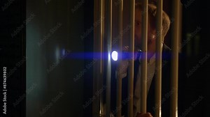 A man with a flashlight looks through blinds into a dark room at night, adding mystery and suspense