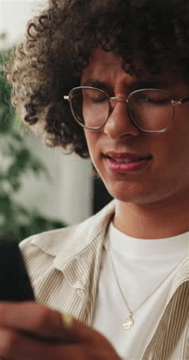 clip-4006636019-confused-phone-reading-man-home-living-room