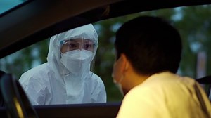 doctor in protective PPE suit using infrared thermometer measuring temperature of man at drive thru station, IR Thermoscan