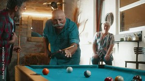 Two senior retired men are having fun playing billiards at home