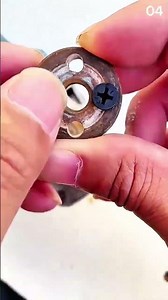 Fingers steady the bobbin plate—one screw locks precision into place