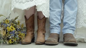 Cowboy boots of a Bride and Groom standing side by side next to flowers. Stock Video
