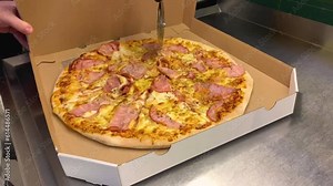 Pizza making of process in restaurant. Cutting pizza in the box. Italian food packaging. Slices of whole prosciutto.