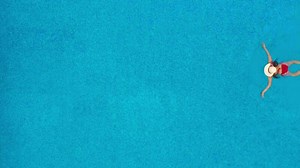 View from the top as a woman in a red swimsuit swims in the pool