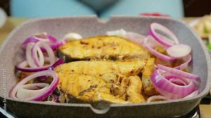 Female hand puts into the fish sliced onions and cherry tomato rings. time laps