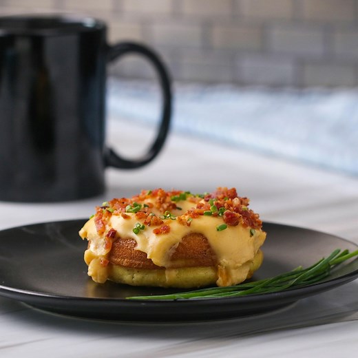 This light and fluffy savory donut is made with an egg souffle base, then topped with a creamy cheddar cheese sauce, crispy bacon crumbles, and freshly chopped chives for a quick and easy breakfast you can eat on the go, or even entertain a brunch crowd with! Recipe: https://tasty.co/recipe/bacon-egg-and-cheese-donuts | Tasty