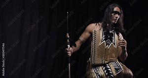 Muscular native american man in traditional costume is holding a spear, 4k