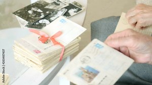 Close-up of the old man's hands opening letter, reading old letters