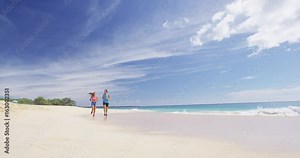 Runners running on beach. Jogging couple training on beach in full body length living healthy active lifestyle. Asian runner woman and fit male fitness athlete on run. Slow motion.