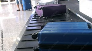 Airport baggage claim with luggage spinning around conveyor. Blurred man taveler takes her suitcase from the conveyor at the airport and leaves. Closeup of him hands. 3840x2160