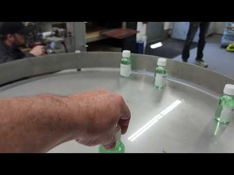 IQ-BTL Single Station Bottle Filling Machine filling and labeling a 125ml bottle