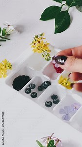 POV, woman creating flower ice cubes, placing tiny flowers, ice cube tray, fruits and flowers, DIY flower ice, floral ice cubes, creative ice cubes, summer drink prep, frozen flowers, floral ice DIY,