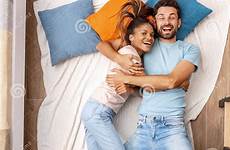 lying laughing hugging cheerful mixed race couple bed woman young man top preview