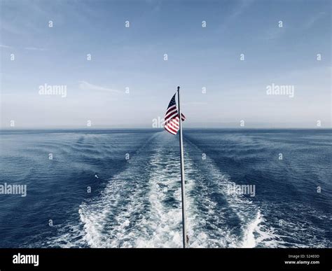 Ferry Boat Wake With American Flag On The Flagpole Disappearing Over