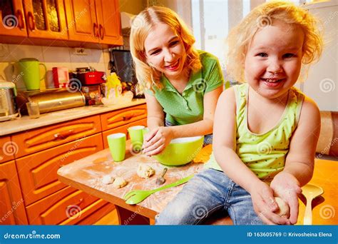mother and her three years old blonde daughter are cooking in a kitchen happy mom and small