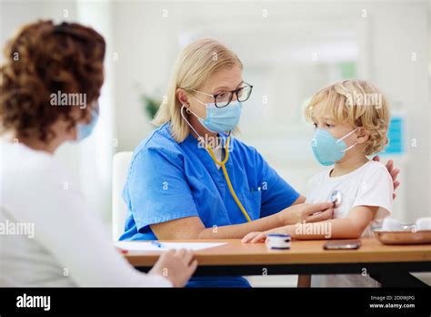 Pediatrician Doctor Examining Sick Child In Face Mask Ill Boy In