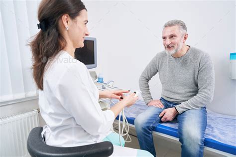 Friendly Young Sonographer Communicating With Patient Before