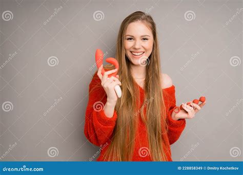 an attractive italian girl depicts the emotion of happiness smiling and holding a red dildo