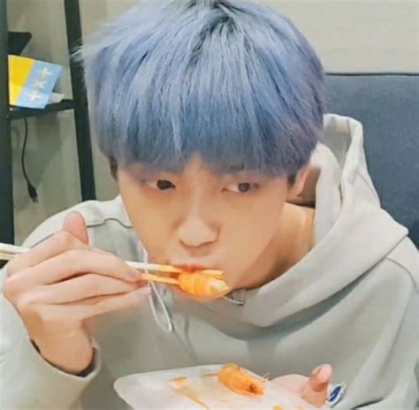 A Man With Blue Hair Eating Food From A White Plate While Wearing A