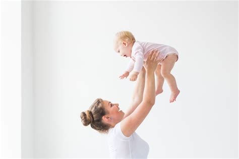 Premium Photo Happy Mother Throws Her Child Up In The Air At Home