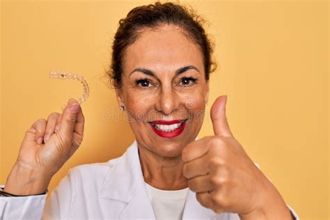 Middle Age Senior Dentist Woman Holding Clear Aligner For Teeth