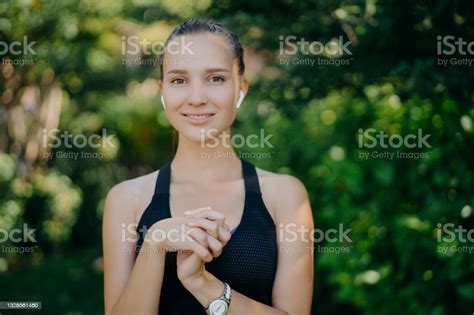 Outdoor Shot Of Pretty Dark Haired Woman Keeps Hands Together Being In