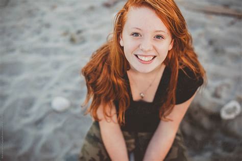 Happy Portrait Of Redhead Teenage Girl Sitting At The Beach By