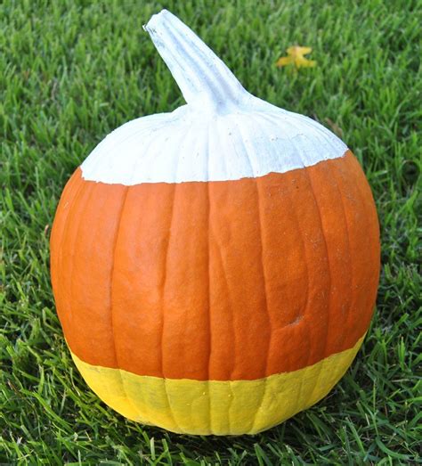 An Orange And White Striped Pumpkin Sitting On Top Of Green Grass In