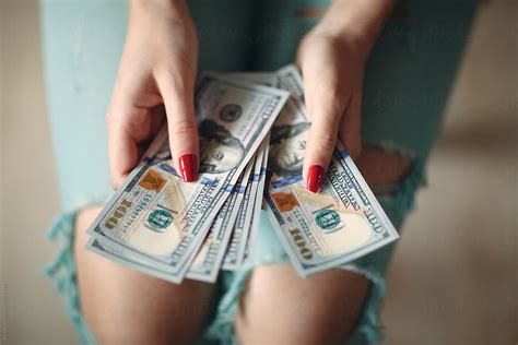 woman holding money dollars by stocksy contributor ilya stocksy