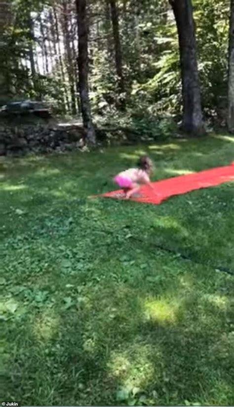 big brother cheers on his little sister after he shows her the best way to go down a slip n