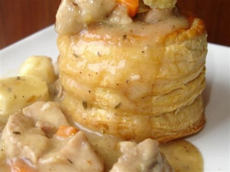 A white plate topped with pancakes covered in gravy and potatoes next