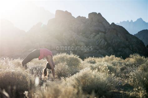 Woman Bending Over Backwards While Practicing Yoga On Field Against