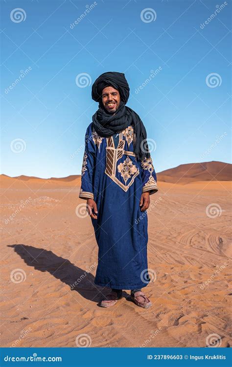 Bedouin Man Wears Traditional Clothes While Standing In Desert Against