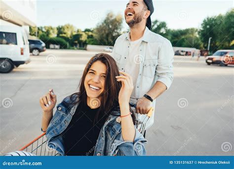 Handsome Guy Carries His Girlfriend In Cart In The Parking Lot Stock