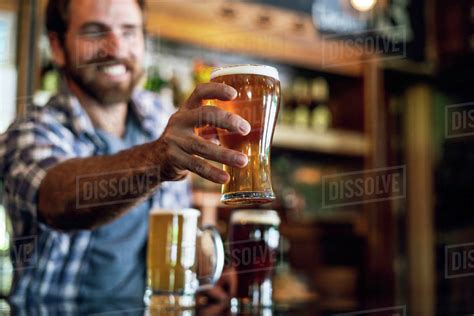 Smiling man serving beer - Stock Photo - Dissolve