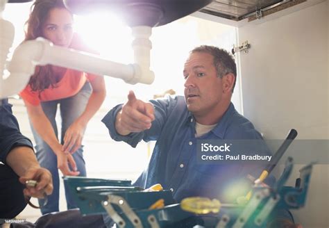 Plumbers Working On Pipes Under Sink Stock Photo Download Image Now