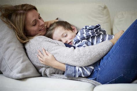 Mother And Son Cuddling On The Couch Stock Photo
