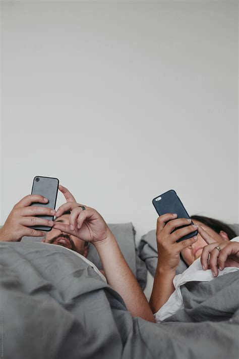 Couple Using Their Phones In Bed By Rob And Julia Campbell Stocksy United
