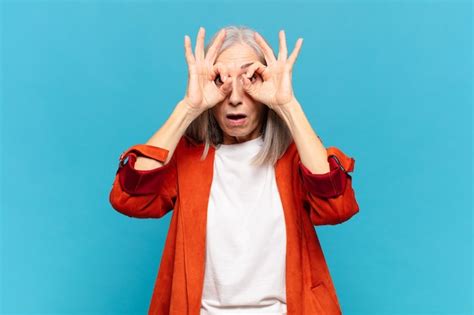 Premium Photo Middle Age Woman Feeling Shocked Amazed And Surprised Holding Glasses With