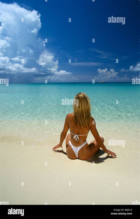 Cayman Islands Grand Cayman Woman In Thong Sitting On Beach At Stock Photo Alamy