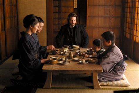 A Group Of People Sitting Around A Wooden Table Eating Food From Bowls