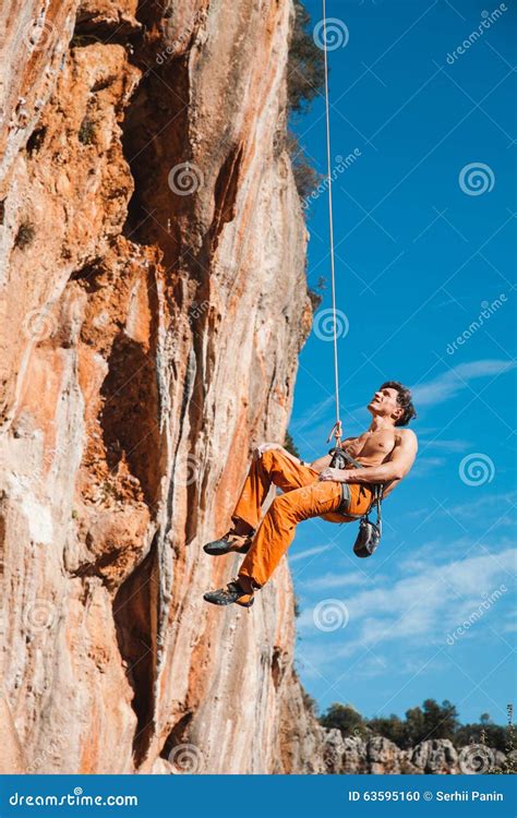 Rock Climber Hanging On Belay Rope Over The Mountains Stock Photo