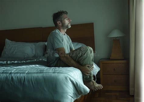 Dramatic Lifestyle Portrait Of Handsome Guy Sitting On Bed Feeli Stock